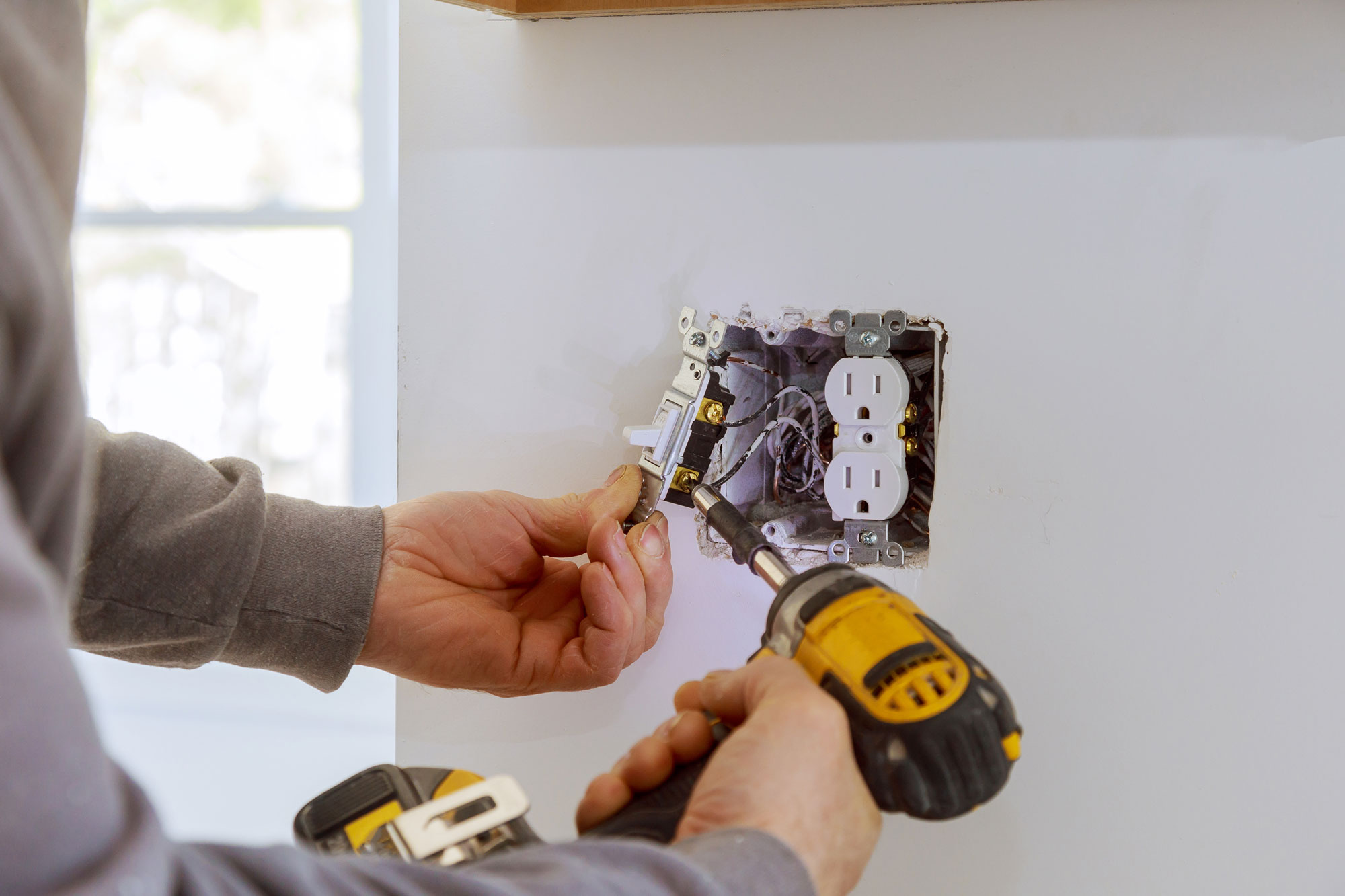 Electrician repairing and testing a wall outlet